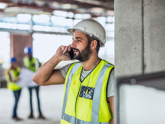 Arbeiter auf Baustelle im Gespräch am Handy