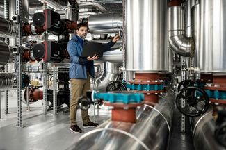 Techniker an Heizungsanlage mit Laptop