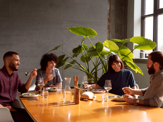 vier Personen die zusammen am Tisch sitzen und ein Essen zusammen geniessen in einem schönen Esszimmer